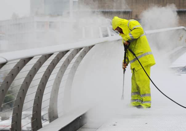 A worker using a high temperature pressure washer to remove chewing gum