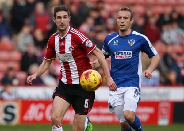 Blades' Chris Basham and Oldham's Liam Kelly battle for the ball.