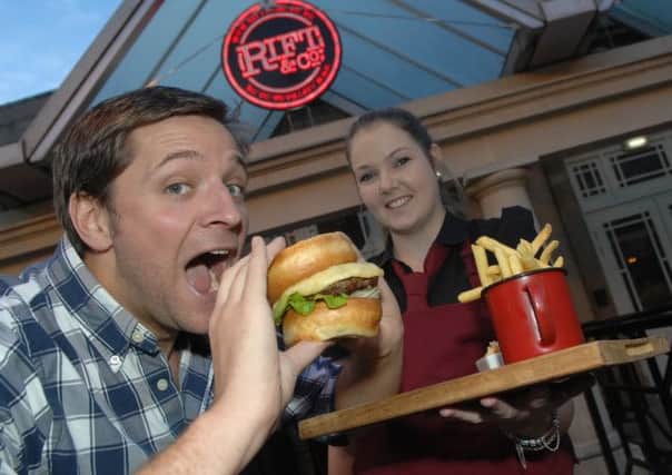 Rift and Co manager Jeremy Ambrose tucks into a Yorkshire pudding burger while bar staff member Jaimee Usher looks on. (1411104AM1)