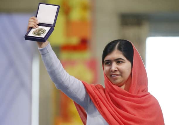Malala Yousafzai holds up her medal during the Nobel Peace Prize award ceremony in Oslo