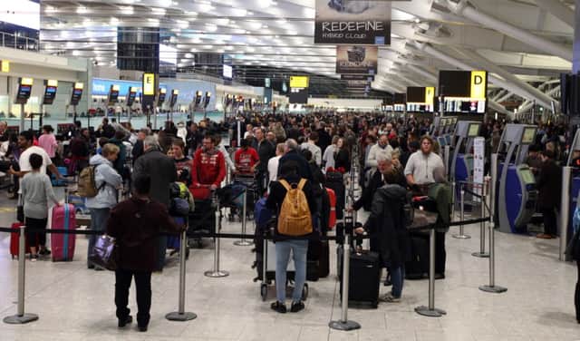 People wait at Terminal 5 of Heathrow Airport as dozens of flights have been cancelled nationwide and many others delayed after a computer failure at the headquarters of air traffic control company Nats.