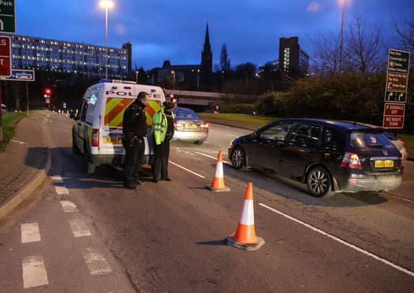 One lane of Derek Dooley Way is closed off by police after two men were shot as they sat inside a vehicle. Picture: Ross Parry Agency