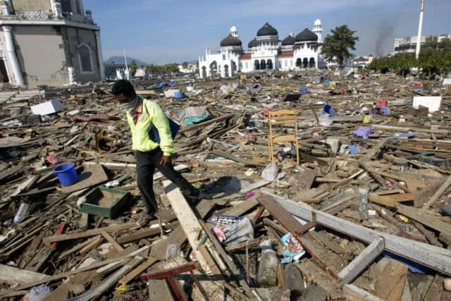 An Acehnese man walks through debris near the Baiturrahman Grand Mosque in Banda Aceh, about 240 kilometers (150 miles) from the earthquake's epicenter, Indonesia.