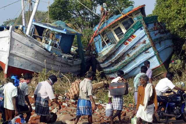 Villagers walk with their belongings past two boats that were washed ashore by tidal waves at Nagappattinam, in the southern Indian state of Tamil Nadu. 
AP Photo/Gautam Singh, File