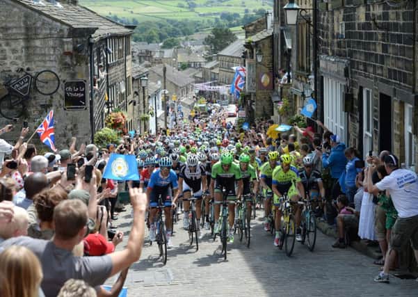 The peloton rides up Main Street as stage two of the Tour de France passes through Haworth last July