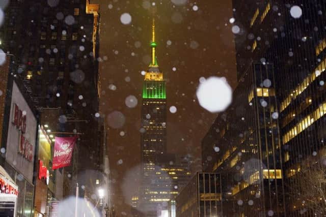 Snow falls around the Empire State Building in midtown Manhattan
