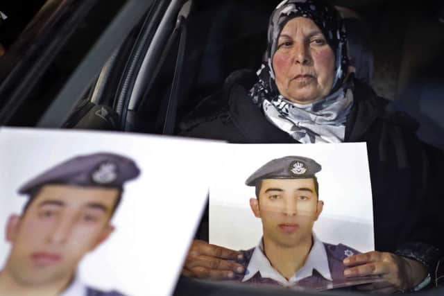 Anwar al-Tarawneh, center, the wife of Jordanian pilot, Lt. Muath al-Kaseasbeh, holds a poster of him with Arabic that reads, "we are all Muath," during a protest in Amman, Jordan