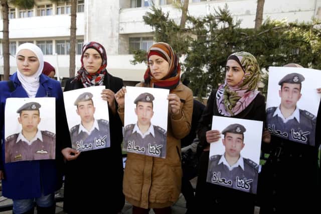 Anwar al-Tarawneh, center, the wife of Jordanian pilot, Lt. Muath al-Kaseasbeh, holds a poster of him with Arabic that reads, "we are all Muath," during a protest in Amman, Jordan