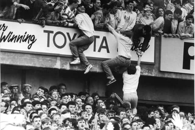 Liverpool fans scramble upwards from the crush on the Leppings Lane terrace.
