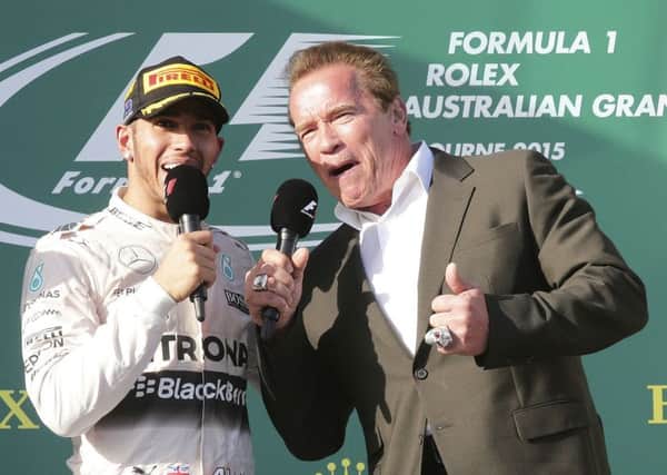 Mercedes driver Lewis Hamilton, left, of Britain speaks with actor Arnold Schwarzenegger on the podium after winning the season-opening Australian Formula One Grand Prix at Albert Park in Melbourne. (AP Photo/Rob Griffith)
