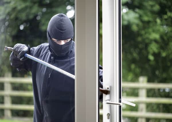 A generic photo of a burglar breaking into a house.