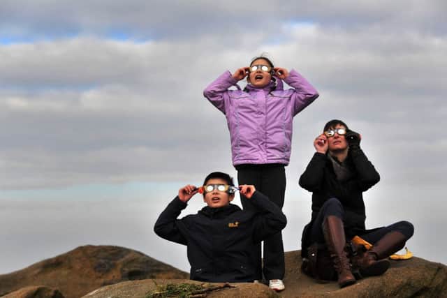 The Kraam family from Menston watching the eclipse, through the clouds from Otley Chevin.   Picture: Bruce Rollinson