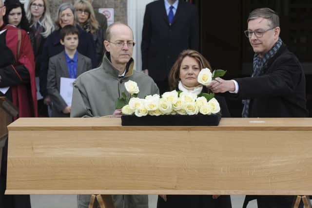 Descendants of Richard III, nephew 16 times removed Michael Ibsen, left, and his brother Jeff Ibsen, right, and niece 18 times removed Wendy Duldig place white roses on a coffin bearing the remains of Richard III outside the Fielding Johnson Building at the University of Leicester