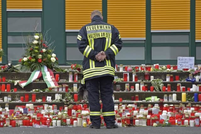 A firefighter stands in  front of candles and flowers on the steps to the Joseph-Koenig high school  in Haltern, Germany