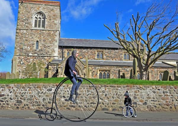Christian Richards goes for a spin on the 60inch wheel penny farthing he has built while son Austin, 2,looks on with his tiny version.
