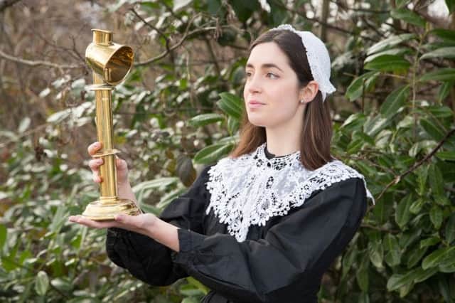 An auction house worker dressed as Florence Nightingale holding a 150-year-old lamp that belonged to the pioneering health reformer.