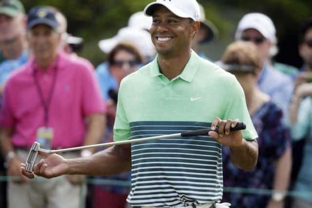 Tiger Woods smiles as waits to putt during a practice round for the Masters golf tournament Wednesday, April 8, 2015, in Augusta, Ga. (AP Photo/Darron Cummings)