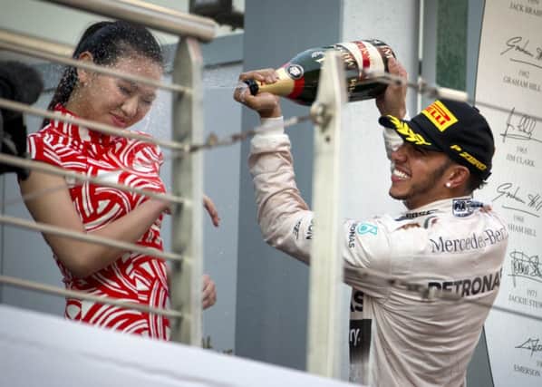 Mercedes driver Lewis Hamilton of Britain sprays champagne on a track attendant on the podium after winning the Chinese Formula One Grand Prix.
