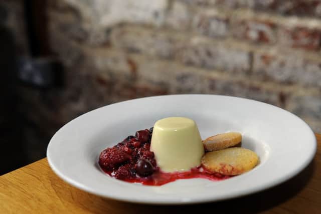 A dessert of vanilla panna cotta with berry compote and shortbread