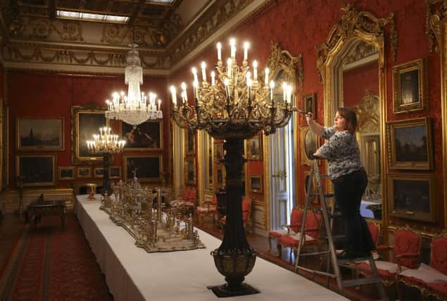 English Heritage historic property steward Jennifer Watling cleaning one of the lights in the Waterloo Gallery in Apsley House in London