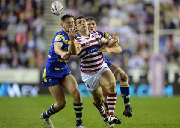 Wigan Warriors Ben Flower loses control of the ball as he is tackled by Warrington Wolves' Ben Currie, left, and Ben Harrison.