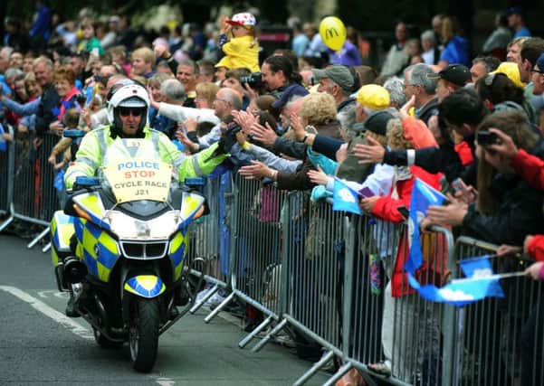 A police outrider high fives fans pack the streets as the Tour de France peloton makes it's way past York Minster on the second day of the tour.
6th July 2014. Picture Jonathan Gawthorpe.