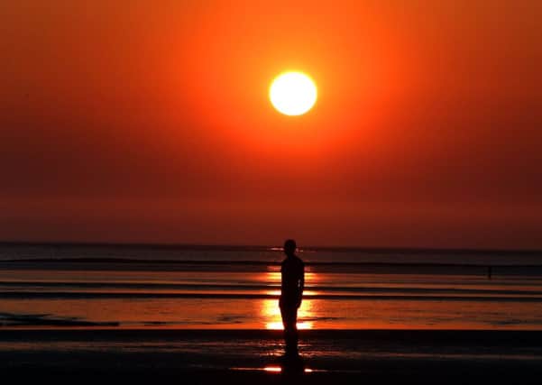The sun sets over one of the Iron Men,  part of the Another Place installation by Anthony Gormley, at Crosby Beach, Merseyside, last night. PRESS ASSOCIATION Photo. Picture date: Monday April 20, 2015. Britain's is set to bask in sunshine today with temperatures expected to equal the holiday resort of Ibiza. See PA story WEATHER Hot. Photo credit should read: Peter Byrne/PA Wire