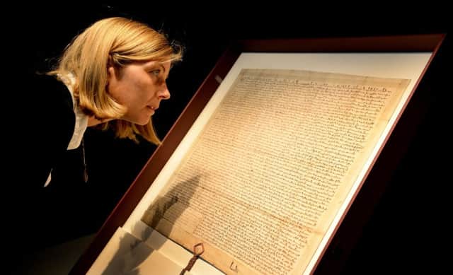 Carline de Stefani, conservator at London Metropolitan Archive, positions a 13th century copy of the Magna Carta during its installation at Heritage Gallery, in the City of London last year.  Pic: Andrew Matthews/PA Wire