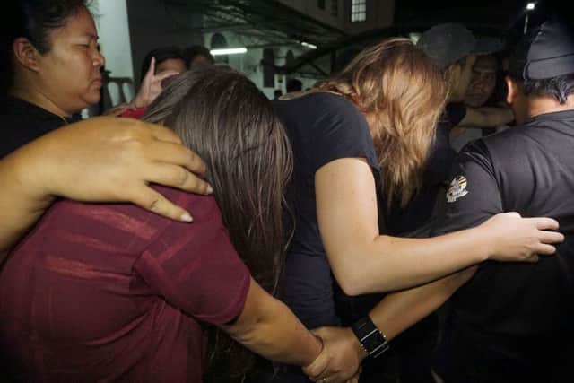 Canadian Danielle Petersen, 22, center right, and left, Eleanor Hawkins, 24, left, of Britain are escorted by police as they leave court in Kota Kinabalu, in eastern Sabah state on Borneo island, Malaysia. Both women were among the 10 people who stripped naked and took photos on Mount Kinabalu on May 30. A local official has said the foreigners behavior caused an earthquake near the mountain last Friday that killed 18 climbers. (AP Photo/Mohd Asraffirdauz Bin Abdullah)