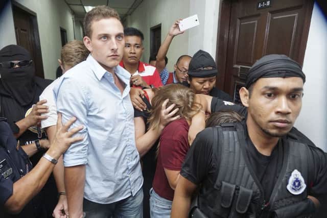 Dutch national Dylan Snel, in blue shirt, center, is escorted by police as he and three others leave the court in Kota Kinabalu, in eastern Sabah state on Borneo island, Malaysia. (AP Photo/Mohd Asraffirdauz Bin Abdullah)