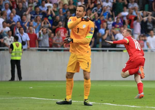 England's Wayne Rooney (right) celebrates scoring his sides third goal of the game as Slovenia goalkeeper Samir Handanovic looks on. Picture: Mike Egerton/PA.