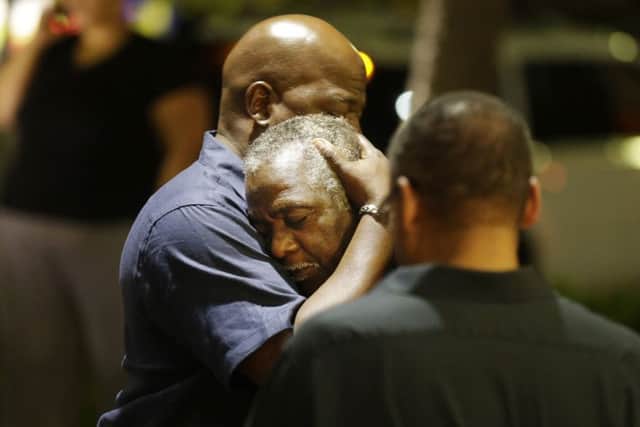 Worshippers embrace following a group prayer across the street from the scene of a shooting in Charleston, S.C. (AP Photo/David Goldman)