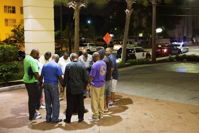 Worshippers gather to pray in a hotel parking lot across the street from the scene of a shooting in Charleston, S.C. (AP Photo/David Goldman)