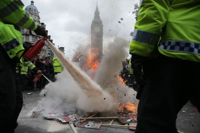 Police extinguish a small fire of burning placards at the End Austerity Now rally in Parliament Square, London.  Photo : Daniel Leal-Olivas/PA Wire