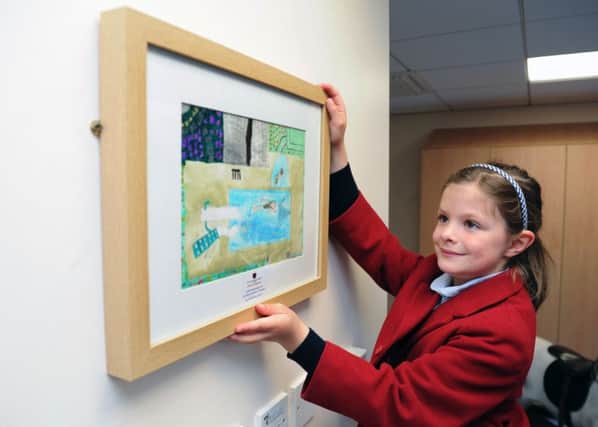Seven-year-old Alice Baldwin hangs her painting of a great family day out in the Valley Gardens on the wall of the newly-refurbished heart unit playroom at Leeds General Infirmary.  Pic: Jonathan Gawthorpe.
