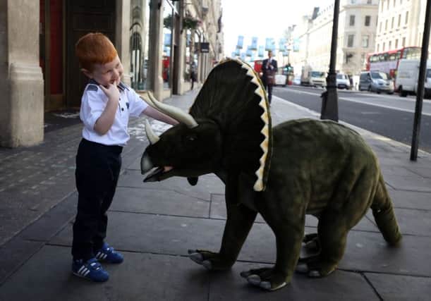 Four-year-old Tristan plays with a Triceratops sit-on dinosaur at Hamleys
