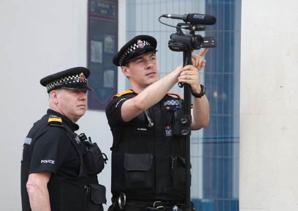 Policemen using a video camera watches the crowds in Guildford High Street in Surrey ahead of the Armed Forces Day parade.