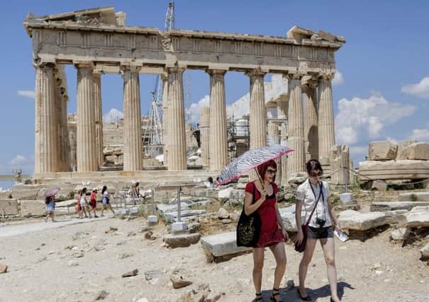 Tourists walk trough the ancient Acropolis hill, with the ruins of the fifth century BC Parthenon temple on the background in Athens (AP Photo/Daniel Ochoa de Olza)