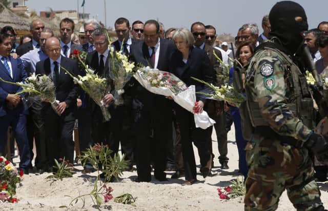 British Home Secretary Theresa May and her French, German and Tunisian counterparts lays flowers at the scene of the attack. (AP Photo/Abdeljalil Bounhar)