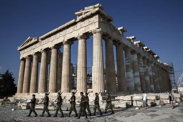 An army contingent carry a Greek flag in front of the Temple of the Parthenon before a hoisting ceremony at the Acropolis Hill in Athens.