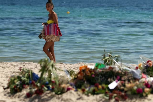 Tourists look at flowers that have been laid on the beach near the RIU Imperial Marhaba hotel in Sousse