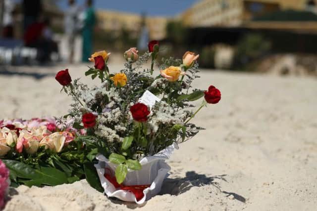 Tourists look at flowers that have been laid on the beach near the RIU Imperial Marhaba hotel in Sousse