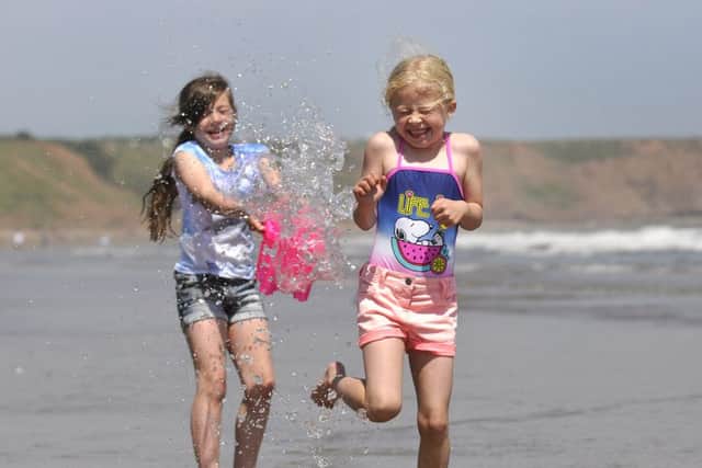 Filey weather.  Kara Alexander  (9)helps cool off her Sister Jodi  (6) in the scorching heat. pic Richard Ponter 152619b