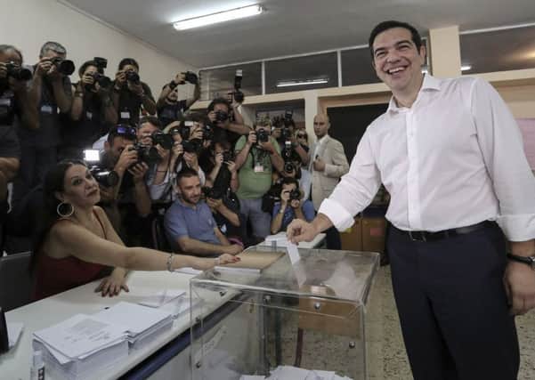 Greece's Prime Minister Alexis Tsipras, right, casts his vote at a polling station in Athens