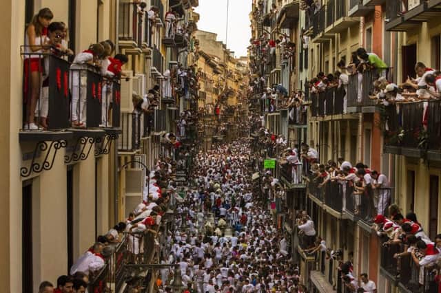 People watch as Jandilla fighting bulls and revelers run during the running of the bulls at the San Fermin festival in Pamplona, Spain