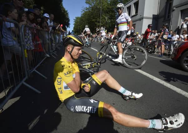 Germany's Tony Martin, wearing the overall leader's yellow jersey, grimaces as he lies on the road with a broken collarbone.