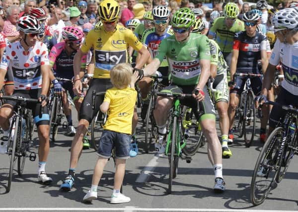 A child high-fives with the four jerseys Australia's Richie Porte, wearing the best climber's dotted jersey, Britain's Christopher Froome, wearing the overall leader's yellow jersey, Germany's Andre Greipel, wearing the best sprinter's green jersey, and Colombia's Nairo Quintana, wearing the best young rider's white jersey, prior to the start of the eleventh stage of the Tour de France cycling race over 188 kilometers (116.8 miles) with start in Pau and finish in Cauterets, France. (AP Photo/Laurent Cipriani)