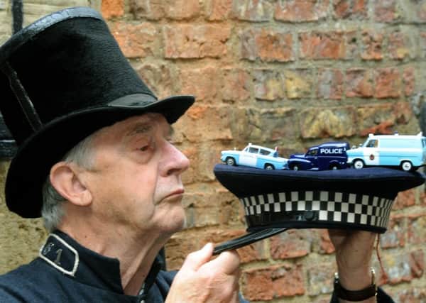 Harry Corps, a volunteer at the  Ripon Police and Prison museum, dressed in 1830s police uniform, with model police vehicles, left to right, a 1950s Ford Anglia, a 1960s  Morris Minor dog van and a 1969 Ford Transit. Pictures: Gary Longbottom.