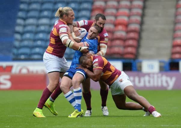 Wakefield Wildcats Jon Molloy is tackled by Huddersfield Giants Eorl Crabtree, Craig Huby and Ukuma Ta'ai. Picture: Anna Gowthorpe