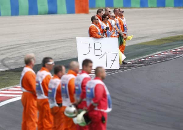 TRIBUTE: Track marshals stay in a minute of silence to pay tribute to late French formula One driver Jules Bianchi prior the start of the Hungarian Grand Prix, a race won by Sebastian Vettel.